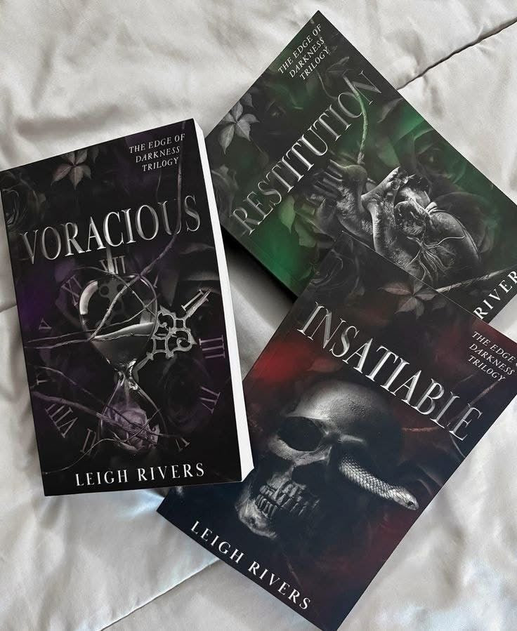 Three books from the 'Vengeful Inhumanity Trilogy' by Leigh Rivers on a textured surface.