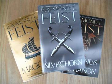 Three books by Raymond E. Feist on a wooden surface