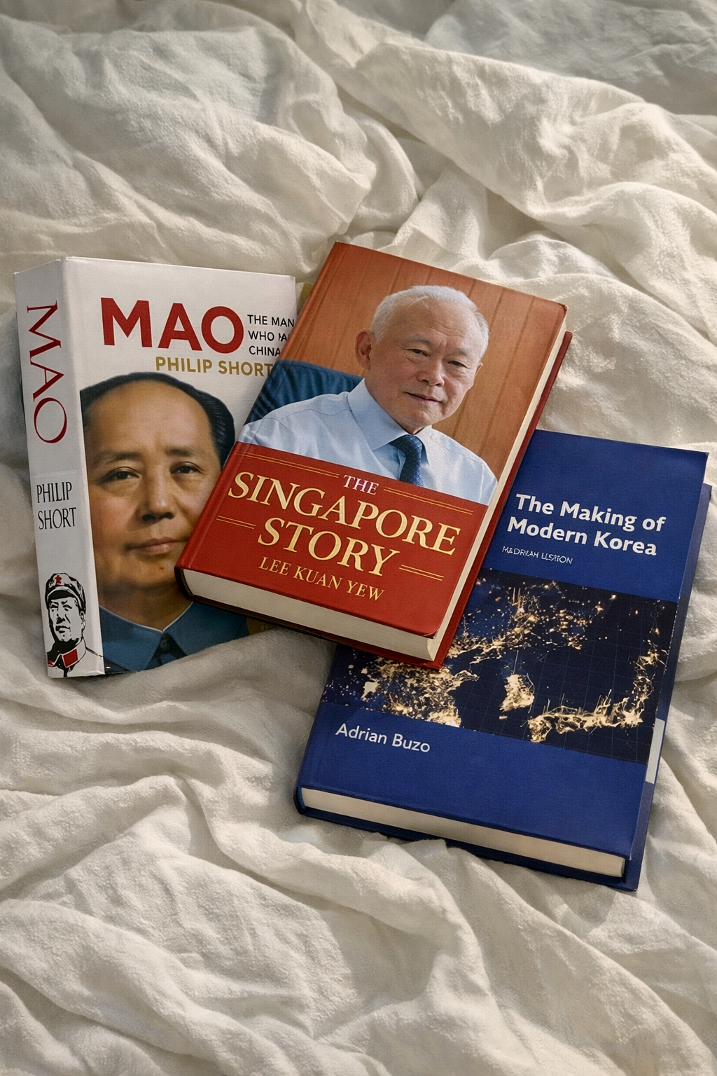 Three books on a textured surface, including 'Mao', 'The Singapore Story', and 'The Making of Modern Korea'.